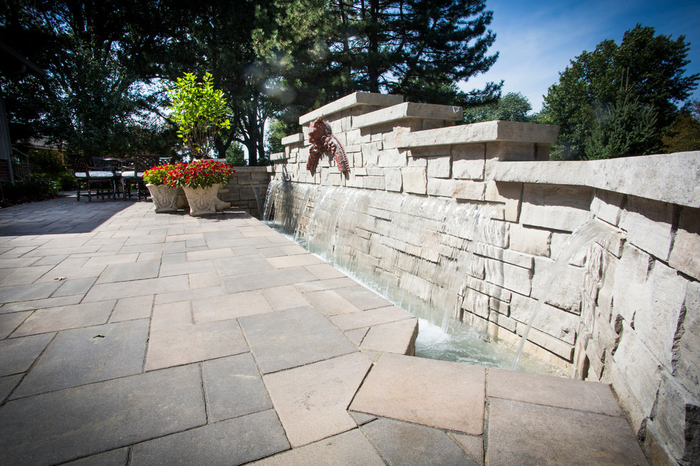 This is an example of a transitional backyard stone water fountain landscape in Omaha.