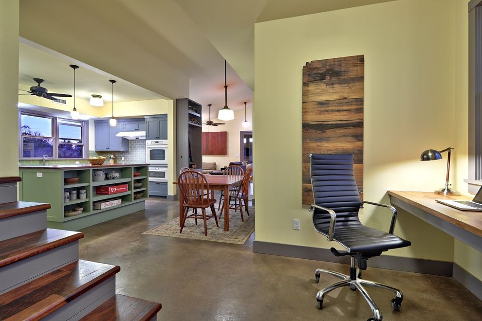 This is an example of a country home office in Austin with a built-in desk, concrete floors and brown floor.