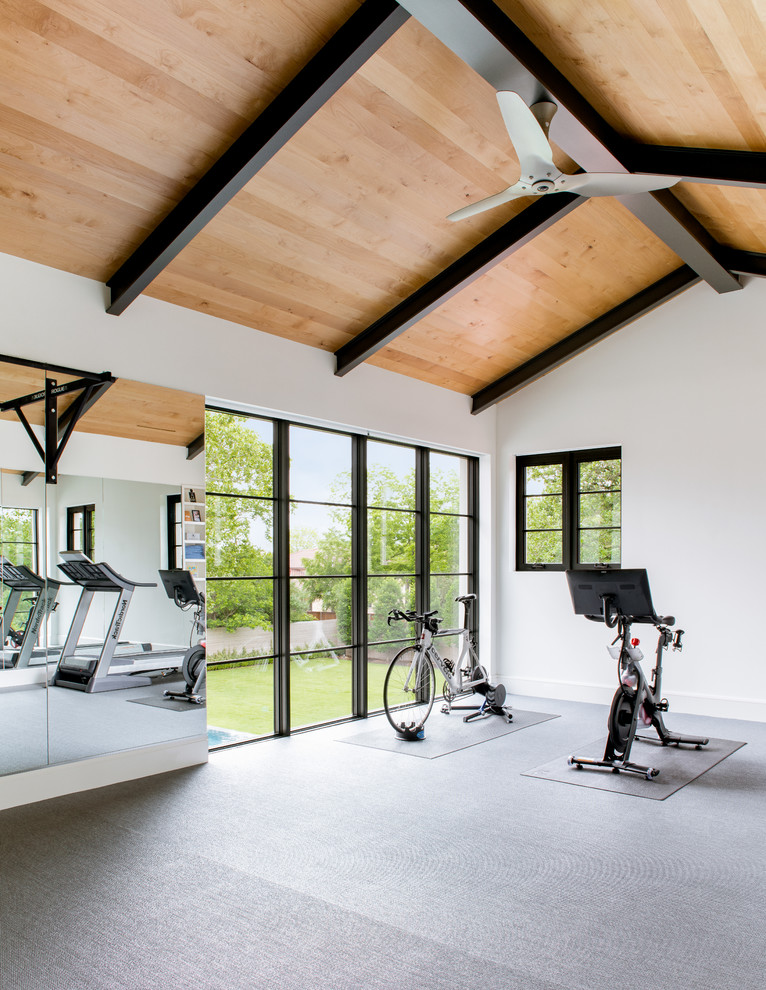 This is an example of a large mediterranean home gym in Dallas with white walls and grey floor.