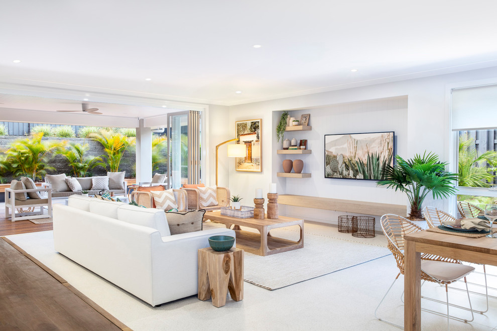 Design ideas for a beach style open concept living room in Brisbane with white walls, medium hardwood floors, a wall-mounted tv and brown floor.