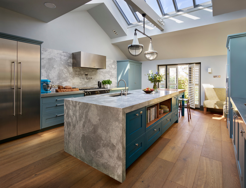 Design ideas for a large transitional kitchen in London with an undermount sink, blue cabinets, grey splashback, stone slab splashback, stainless steel appliances, medium hardwood floors, with island, shaker cabinets, beige floor and quartzite benchtops.