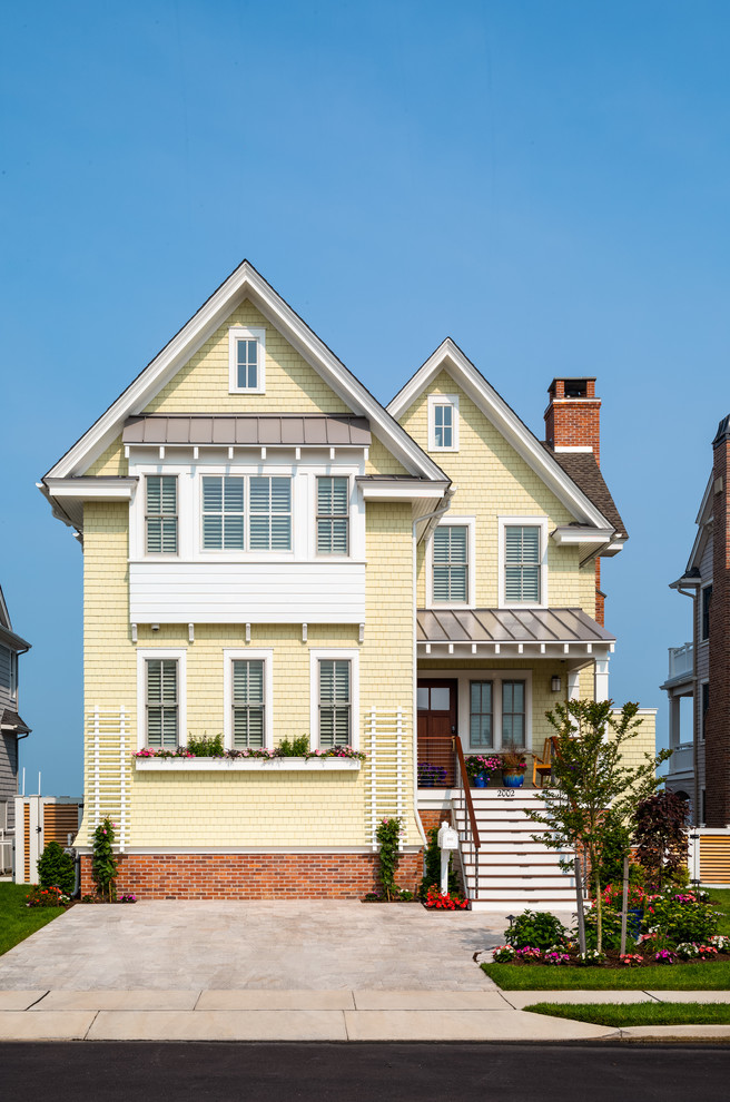 Inspiration for a beach style two-storey yellow house exterior in Philadelphia with a shingle roof.