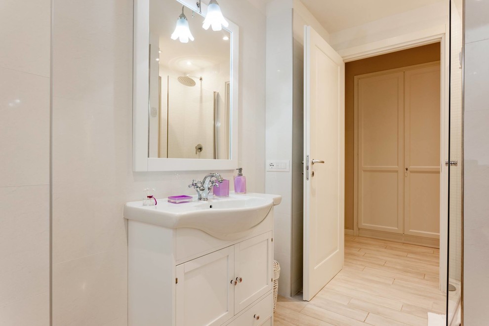 Inspiration for a mid-sized traditional 3/4 bathroom in Rome with white cabinets, a two-piece toilet, white tile, marble, porcelain floors, a trough sink and white floor.