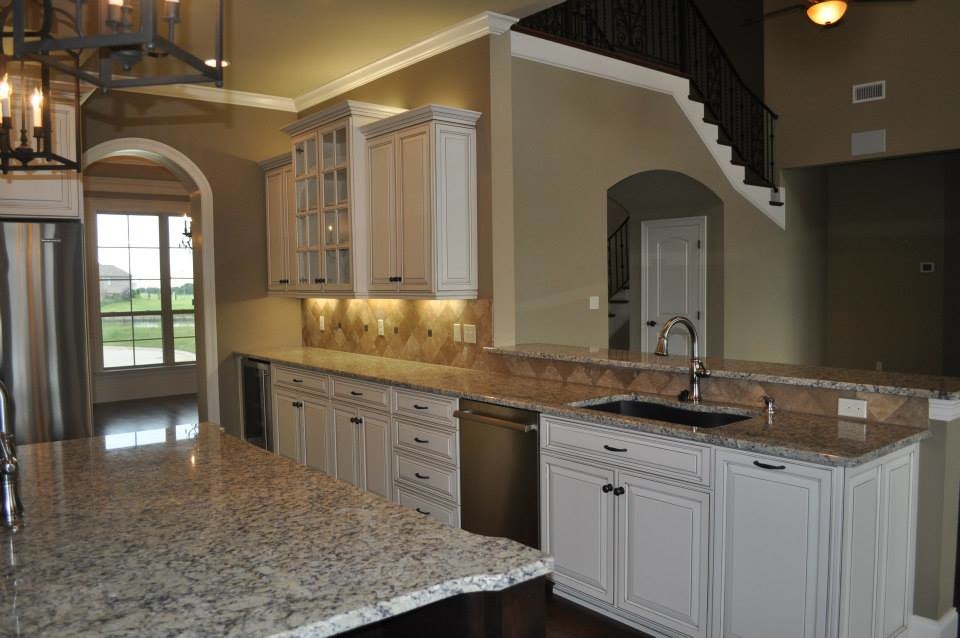 This is an example of a country kitchen in New Orleans with a single-bowl sink, raised-panel cabinets, white cabinets, granite benchtops, beige splashback, ceramic splashback, stainless steel appliances, dark hardwood floors and with island.