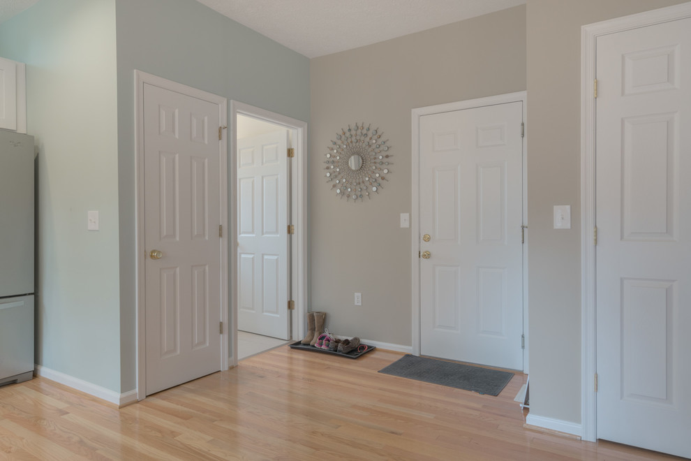 Entryway - mid-sized transitional u-shaped light wood floor entryway idea with an undermount sink, shaker cabinets, white cabinets, quartz countertops, beige backsplash, glass tile backsplash, stainless steel appliances and a peninsula
