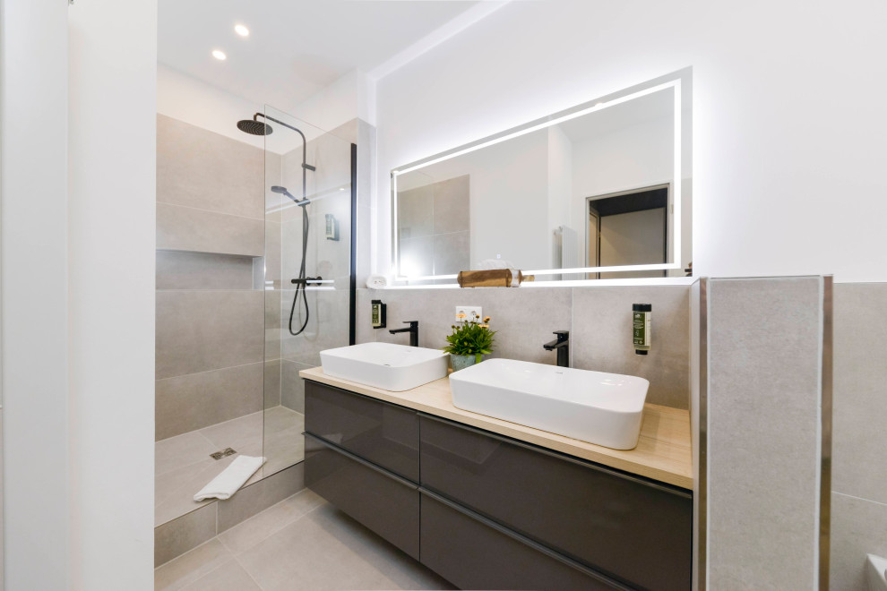 Mid-sized modern 3/4 bathroom in Berlin with flat-panel cabinets, brown cabinets, an open shower, a wall-mount toilet, gray tile, cement tile, white walls, cement tiles, a vessel sink, wood benchtops, grey floor, an open shower, brown benchtops, a niche, a double vanity and a floating vanity.