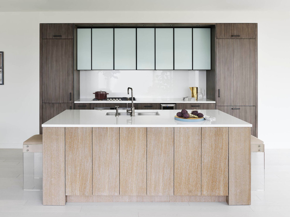 Inspiration for a contemporary galley kitchen in New York with an undermount sink, flat-panel cabinets, dark wood cabinets, recycled glass benchtops, white splashback, glass sheet splashback and with island.