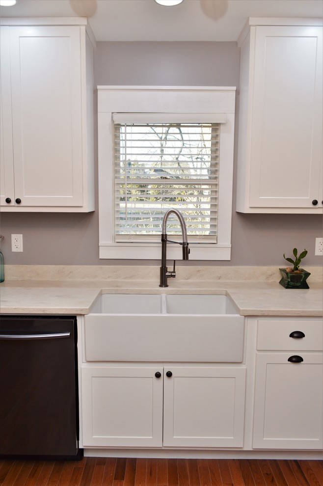 Mid-sized country galley open plan kitchen in Chicago with a farmhouse sink, shaker cabinets, white cabinets, solid surface benchtops, with island and white benchtop.