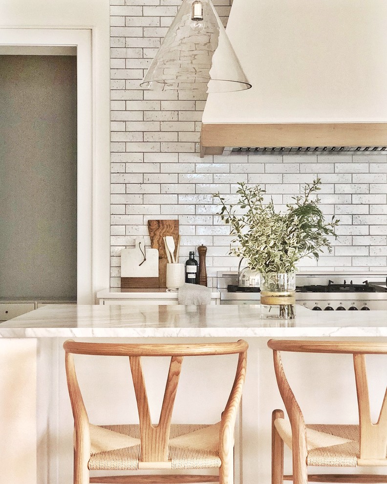 Inspiration for a transitional open plan kitchen in Dallas with a farmhouse sink, shaker cabinets, white cabinets, marble benchtops, white splashback, subway tile splashback, stainless steel appliances, light hardwood floors, with island and white benchtop.