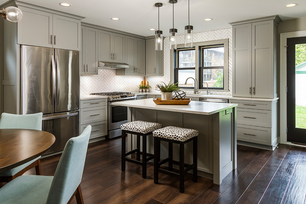 Photo of a small transitional l-shaped eat-in kitchen in Minneapolis with an undermount sink, shaker cabinets, grey cabinets, quartzite benchtops, white splashback, subway tile splashback, stainless steel appliances, dark hardwood floors, with island, brown floor and white benchtop.
