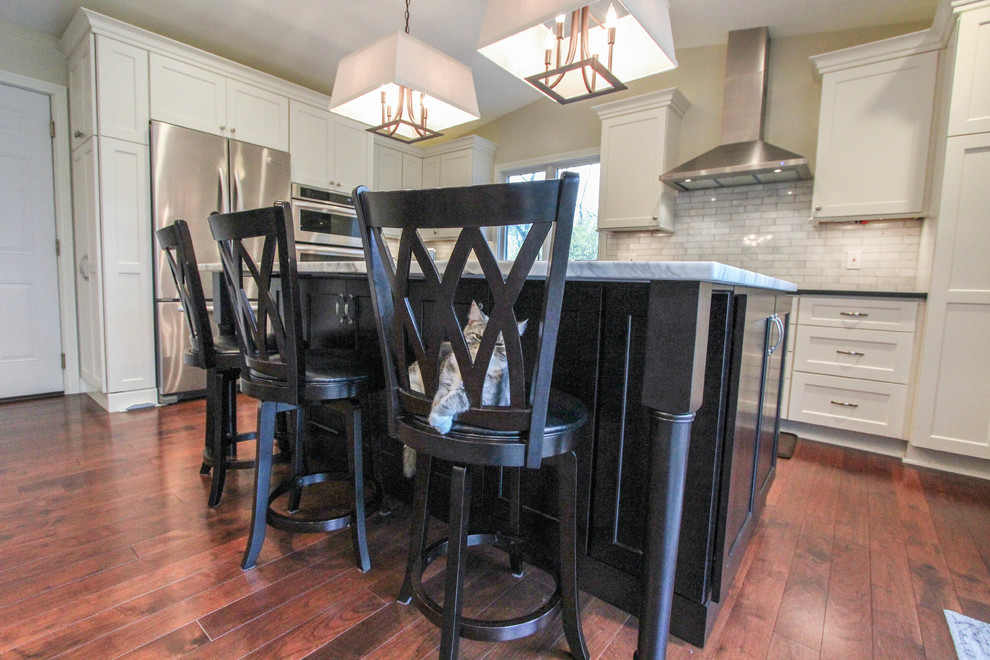 Eat-in kitchen - mid-sized transitional l-shaped medium tone wood floor eat-in kitchen idea in Cincinnati with an undermount sink, recessed-panel cabinets, white cabinets, quartzite countertops, white backsplash, subway tile backsplash, stainless steel appliances and an island