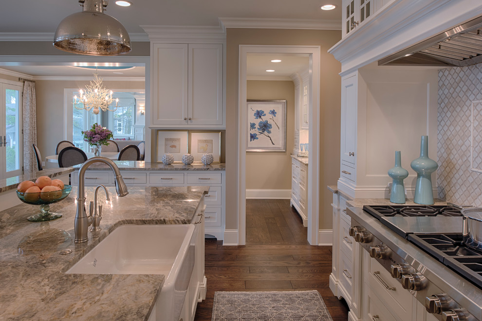This is an example of a mid-sized transitional l-shaped open plan kitchen in Minneapolis with a farmhouse sink, recessed-panel cabinets, white cabinets, granite benchtops, white splashback, ceramic splashback, stainless steel appliances, dark hardwood floors, with island and brown floor.
