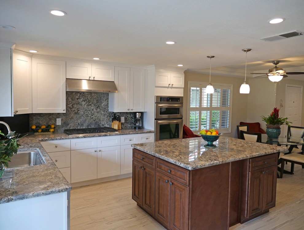 Mid-sized traditional l-shaped eat-in kitchen in Los Angeles with medium wood cabinets, granite benchtops, grey splashback, stainless steel appliances, ceramic floors and with island.