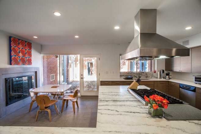 Photo of an expansive midcentury l-shaped kitchen in St Louis with flat-panel cabinets, dark wood cabinets, marble benchtops, white splashback, subway tile splashback, stainless steel appliances, slate floors and with island.