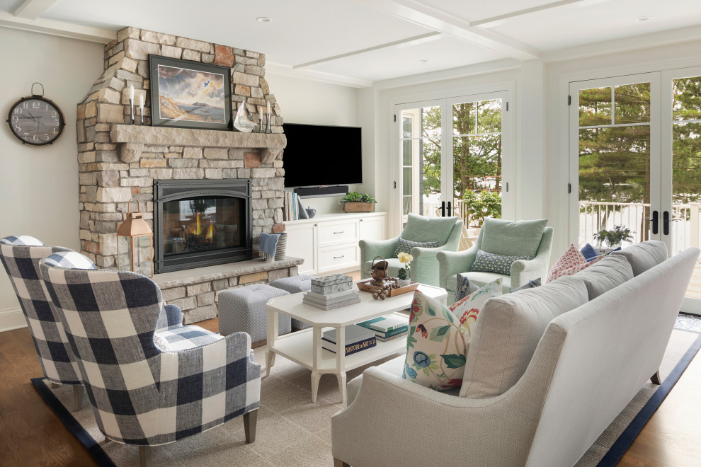 Large beach style open plan games room in Minneapolis with white walls, medium hardwood flooring, a standard fireplace, a stone fireplace surround, a wall mounted tv, brown floors, a coffered ceiling and a chimney breast.