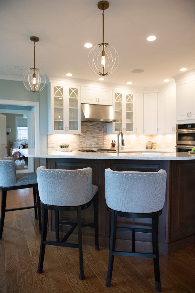 Example of a transitional l-shaped medium tone wood floor eat-in kitchen design in Boston with white cabinets, granite countertops, gray backsplash, stainless steel appliances and an island