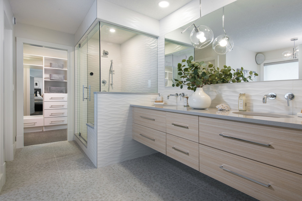 This is an example of a contemporary ensuite bathroom in Calgary with flat-panel cabinets, light wood cabinets, an alcove shower, white tiles, white walls, a submerged sink, engineered stone worktops, grey floors, a hinged door, grey worktops, double sinks and a floating vanity unit.