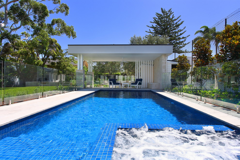 Design ideas for a mid-sized contemporary backyard rectangular pool in Sydney with a pool house and natural stone pavers.