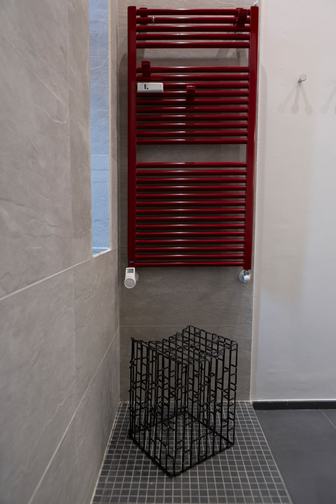 На фото: узкая и длинная ванная комната среднего размера в стиле модернизм с плоскими фасадами, красными фасадами, душем в нише, раздельным унитазом, красной плиткой, каменной плиткой, красными стенами, полом из керамогранита, душевой кабиной, накладной раковиной, столешницей из искусственного кварца, серым полом, открытым душем, белой столешницей, тумбой под одну раковину и подвесной тумбой
