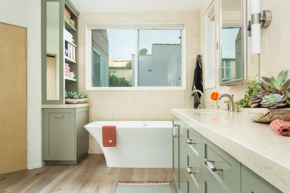 Photo of a large beach style master bathroom in Los Angeles with shaker cabinets, green cabinets, a freestanding tub, a double shower, a bidet, beige tile, marble, beige walls, light hardwood floors, a drop-in sink, marble benchtops, grey floor and a hinged shower door.