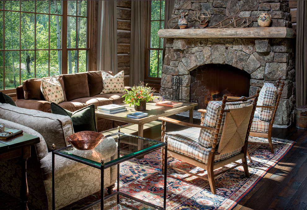 Country living room in Other with dark hardwood floors, a standard fireplace and a stone fireplace surround.