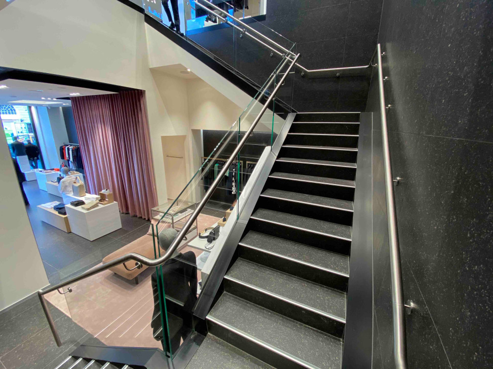 Cette image montre un grand escalier carrelé traditionnel en U avec des contremarches carrelées et un garde-corps en métal.