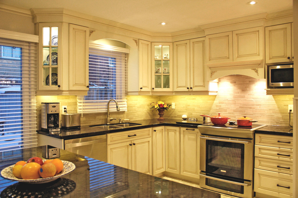 This is an example of a large traditional l-shaped eat-in kitchen in Toronto with an undermount sink, raised-panel cabinets, beige cabinets, granite benchtops, beige splashback, porcelain splashback, stainless steel appliances, porcelain floors and with island.