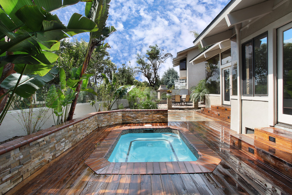 Photo of a tropical pool in Orange County with a hot tub and decking.