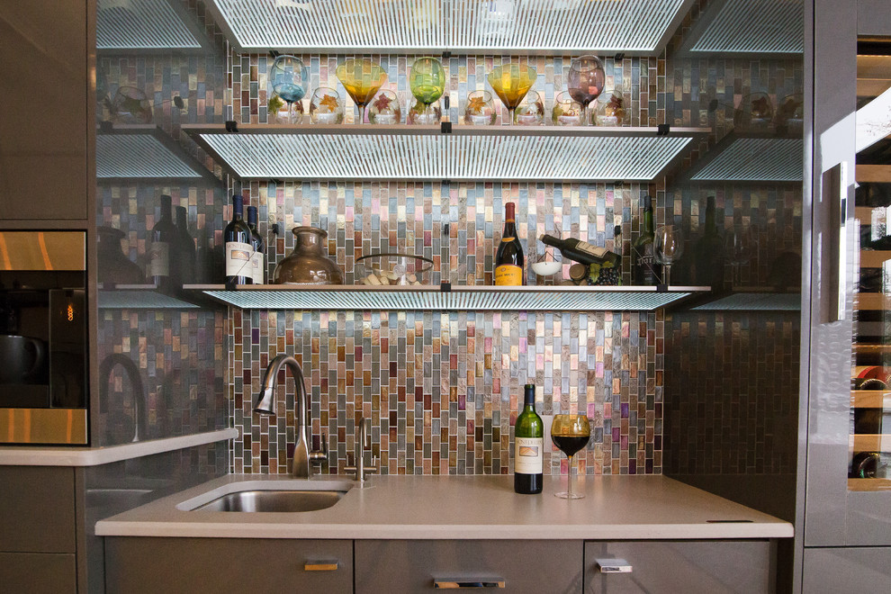 Photo of a mid-sized single-wall wet bar in Charlotte with a drop-in sink, flat-panel cabinets, grey cabinets, quartz benchtops, multi-coloured splashback, mosaic tile splashback and grey benchtop.