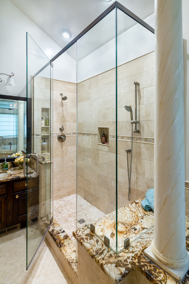 This is an example of a mid-sized mediterranean master bathroom in Philadelphia with raised-panel cabinets, dark wood cabinets, a corner tub, a corner shower, beige tile, stone tile, white walls, slate floors, an undermount sink, marble benchtops, beige floor, a hinged shower door and brown benchtops.