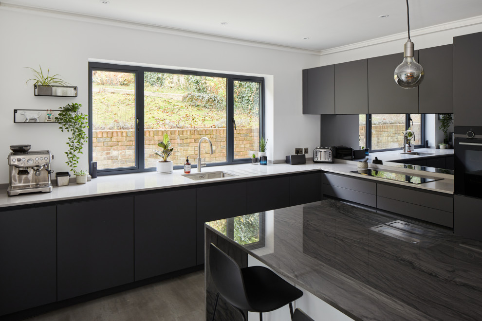 Foto di una cucina minimal di medie dimensioni con lavello sottopiano, ante lisce, ante grigie, paraspruzzi con lastra di vetro e elettrodomestici in acciaio inossidabile
