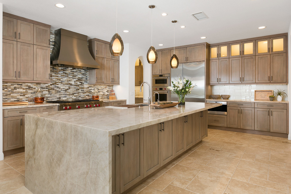 This is an example of a large transitional l-shaped open plan kitchen in San Diego with a single-bowl sink, recessed-panel cabinets, grey cabinets, quartzite benchtops, multi-coloured splashback, glass tile splashback, stainless steel appliances, travertine floors, with island, beige floor and beige benchtop.