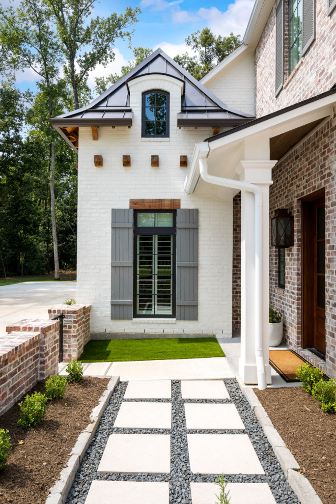 Large two-storey brick white house exterior in Houston with a hip roof, a mixed roof and a grey roof.
