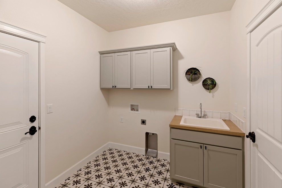Mid-sized midcentury galley dedicated laundry room in Other with a drop-in sink, shaker cabinets, grey cabinets, laminate benchtops, white walls, ceramic floors, multi-coloured floor and brown benchtop.