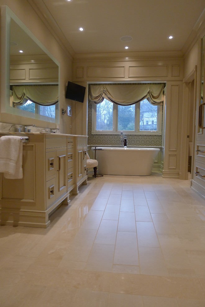 This is an example of a transitional bathroom in Indianapolis with an undermount sink, furniture-like cabinets, beige cabinets, marble benchtops, a freestanding tub, an alcove shower, a one-piece toilet, beige tile and porcelain tile.