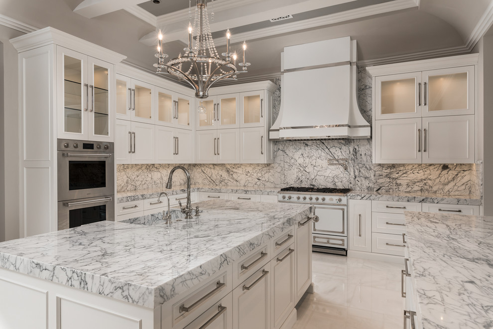 Expansive transitional u-shaped separate kitchen in Phoenix with a farmhouse sink, recessed-panel cabinets, white cabinets, marble benchtops, multi-coloured splashback, marble splashback, stainless steel appliances, marble floors, multiple islands, white floor and green benchtop.