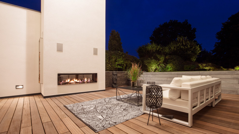 Inspiration for a large contemporary backyard deck in Dortmund with with fireplace and no cover.