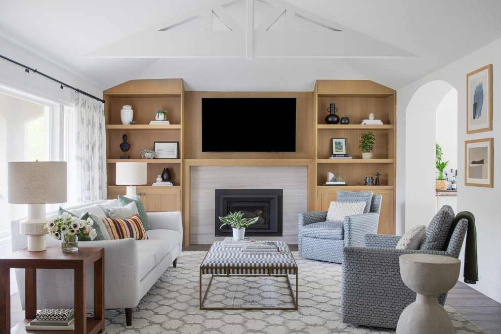 Example of a mid-sized transitional dark wood floor and vaulted ceiling family room design in San Francisco with white walls, a standard fireplace, a stone fireplace and a wall-mounted tv