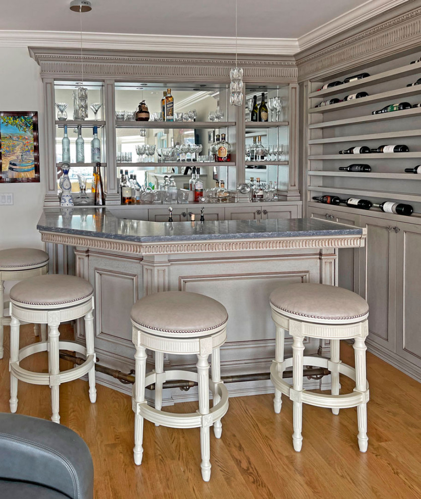 Design ideas for a small traditional l-shaped seated home bar in New York with an integrated sink, shaker cabinets, grey cabinets, quartz benchtops, medium hardwood floors, brown floor and grey benchtop.