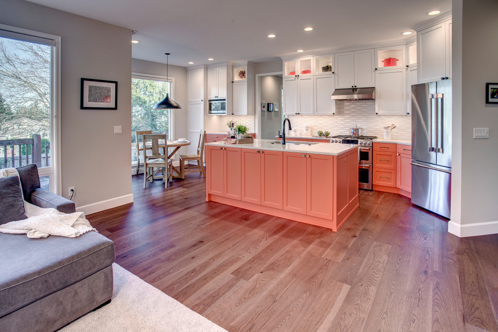 Inspiration for a transitional single-wall kitchen in Seattle with an undermount sink, shaker cabinets, orange cabinets, quartz benchtops, white splashback, ceramic splashback, stainless steel appliances, medium hardwood floors, with island, brown floor and grey benchtop.
