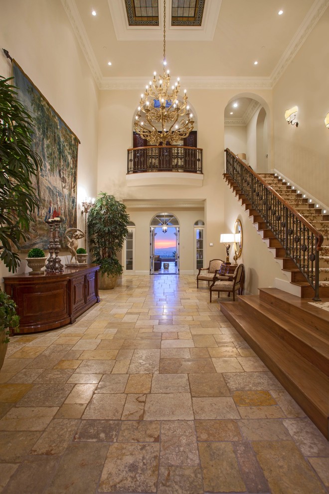Photo of an expansive mediterranean foyer in Orange County with beige walls, limestone floors and a double front door.