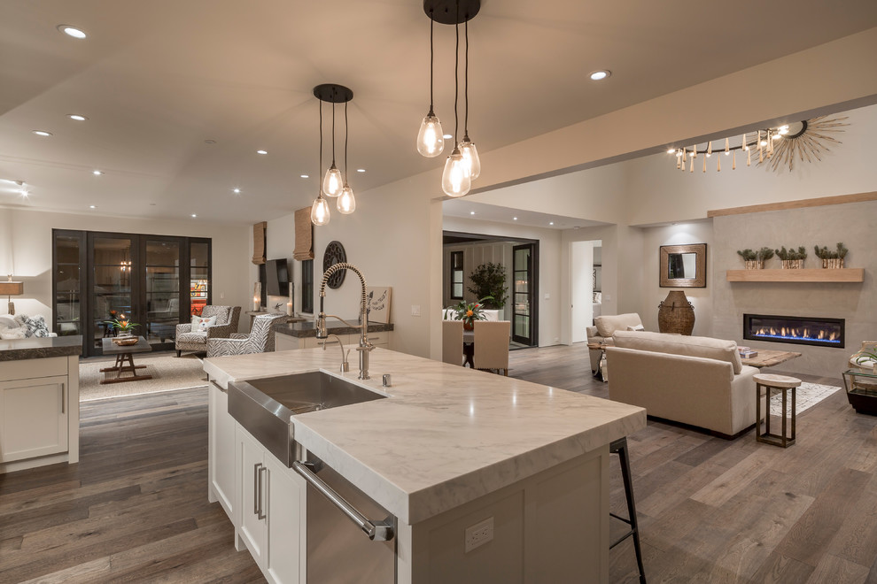 This is an example of a large country u-shaped open plan kitchen in San Francisco with a farmhouse sink, shaker cabinets, white cabinets, marble benchtops, stainless steel appliances, dark hardwood floors, with island, brown floor and multi-coloured benchtop.