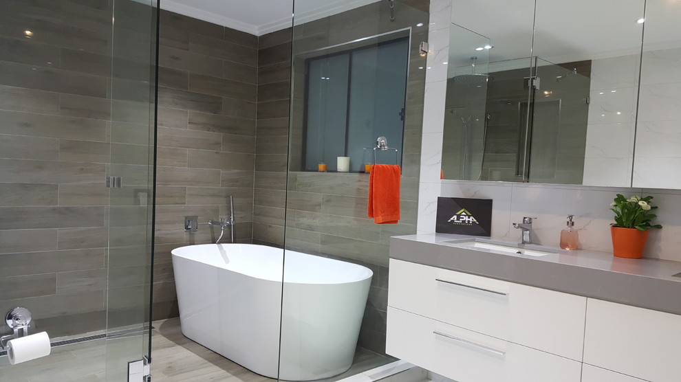 This is an example of a large modern master bathroom in Sydney with flat-panel cabinets, white cabinets, a freestanding tub, an open shower, a two-piece toilet, brown tile, porcelain tile, brown walls, porcelain floors, an undermount sink and engineered quartz benchtops.
