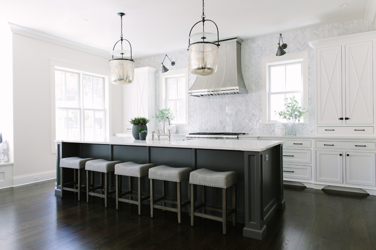 Transitional galley kitchen in Chicago with shaker cabinets, white cabinets, white splashback, marble splashback, panelled appliances, dark hardwood floors, with island and brown floor.