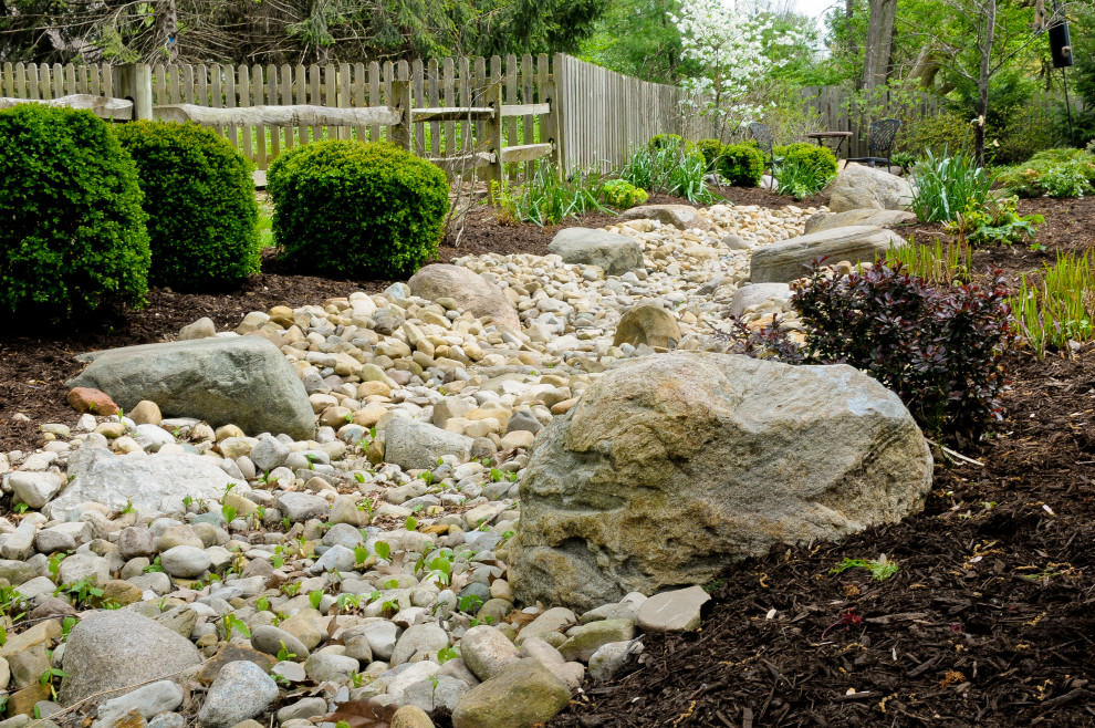 Foto di un grande giardino xeriscape tradizionale esposto in pieno sole dietro casa con sassi di fiume e sassi e rocce