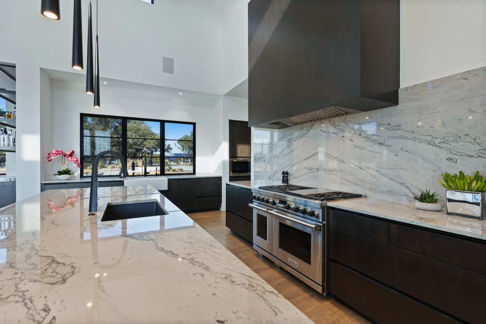 Huge one-story multicolored, medium tone wood floor and brown floor eat-in kitchen photo with a farmhouse sink, flat-panel cabinets, dark wood cabinets, stainless steel appliances, an island and white countertops