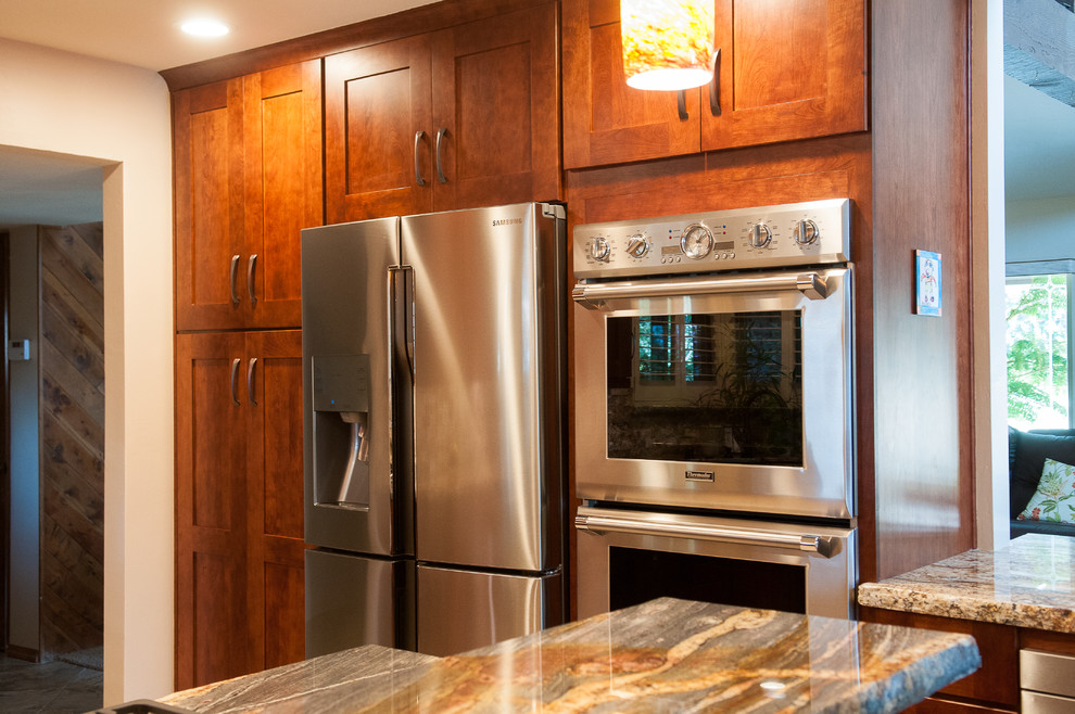 Example of a mid-sized mountain style u-shaped slate floor eat-in kitchen design in Burlington with an undermount sink, shaker cabinets, dark wood cabinets, granite countertops, beige backsplash, stone tile backsplash, stainless steel appliances and a peninsula