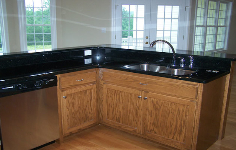 Example of a large medium tone wood floor kitchen design with recessed-panel cabinets, medium tone wood cabinets, granite countertops and stainless steel appliances