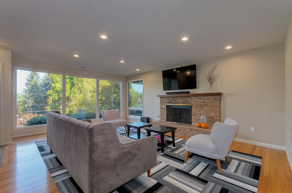 Mid-sized contemporary open concept living room in Portland with beige walls, medium hardwood floors, a standard fireplace, a stone fireplace surround and a wall-mounted tv.