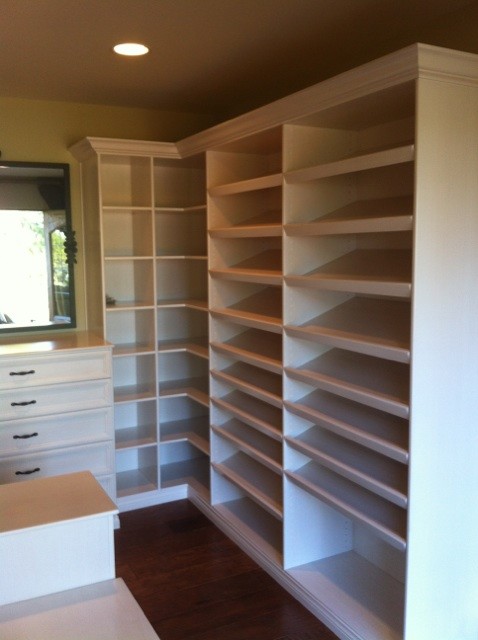 Photo of a large women's dressing room in Los Angeles with recessed-panel cabinets, white cabinets, medium hardwood floors and brown floor.